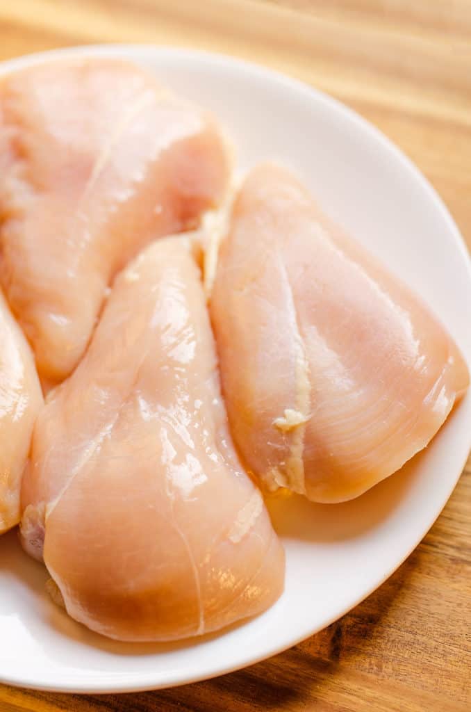 raw boneless skinless chicken breasts on white plate