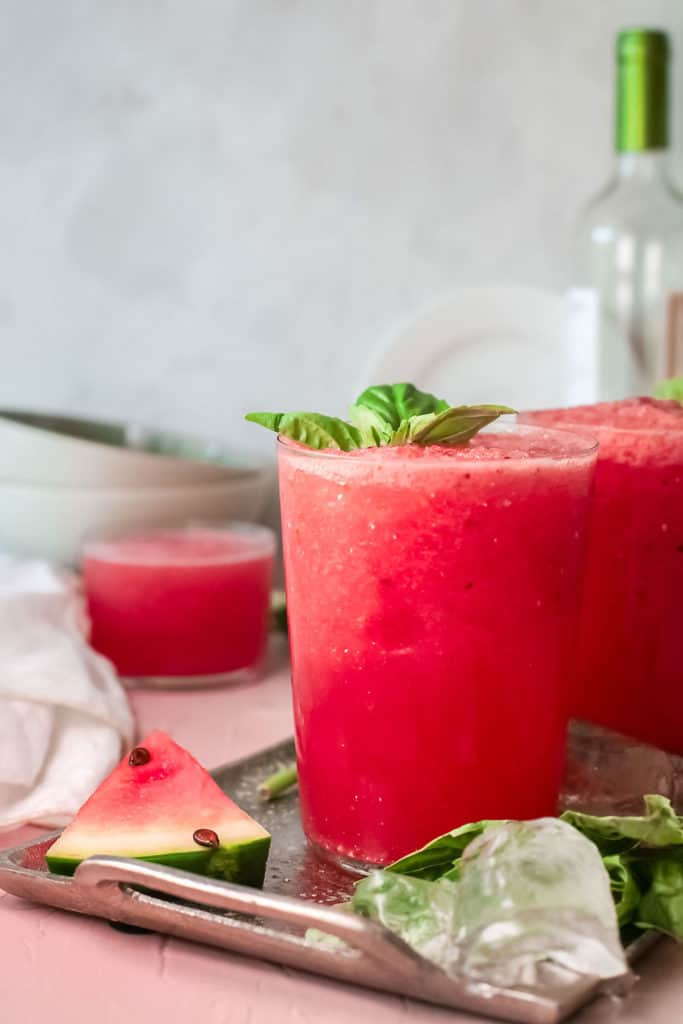 watermelon wine slushie in glass tumbler topped with basil