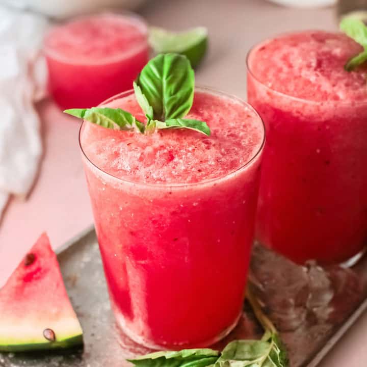 watermelon wine slushies on table with basil leaves and watermelon wedges