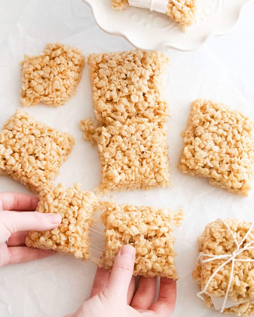 brown butter rice krispie treats on table and hands pulling two bars apart