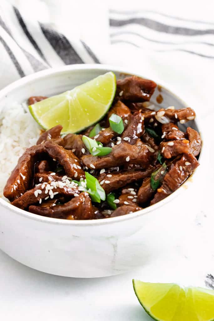 bowl of sesame ginger beef with lime wedge