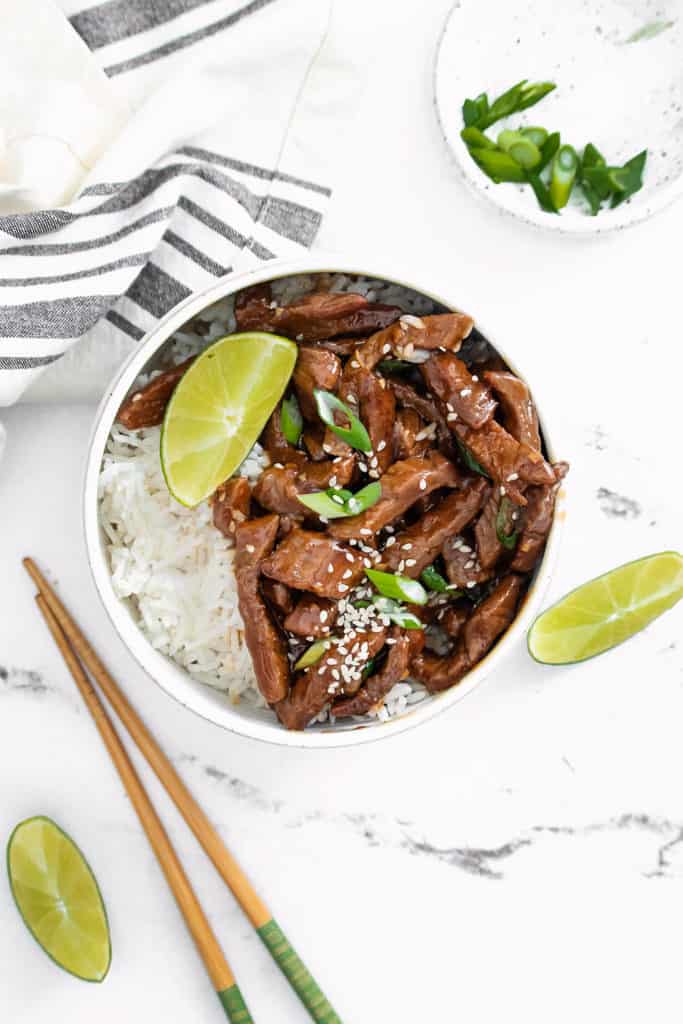 bowl of sesame ginger beef with rice in bowl on table