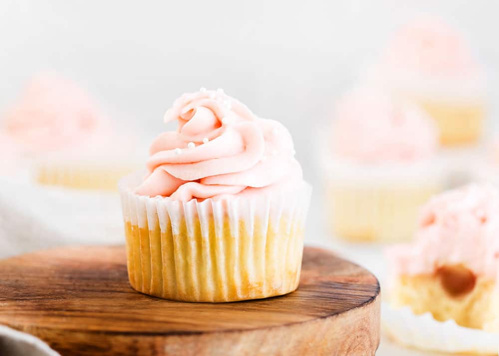 vanilla cupcake topped with swirl of rhubarb buttercream and sprinkles