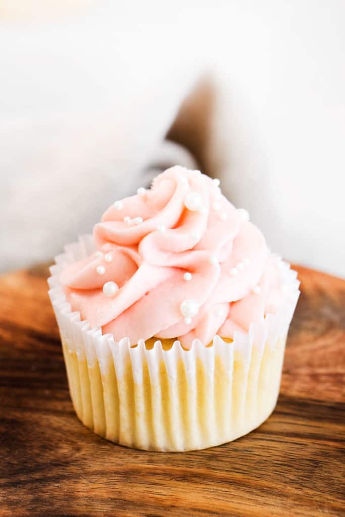 vanilla cupcake topped with swirl of rhubarb buttercream and sprinkles