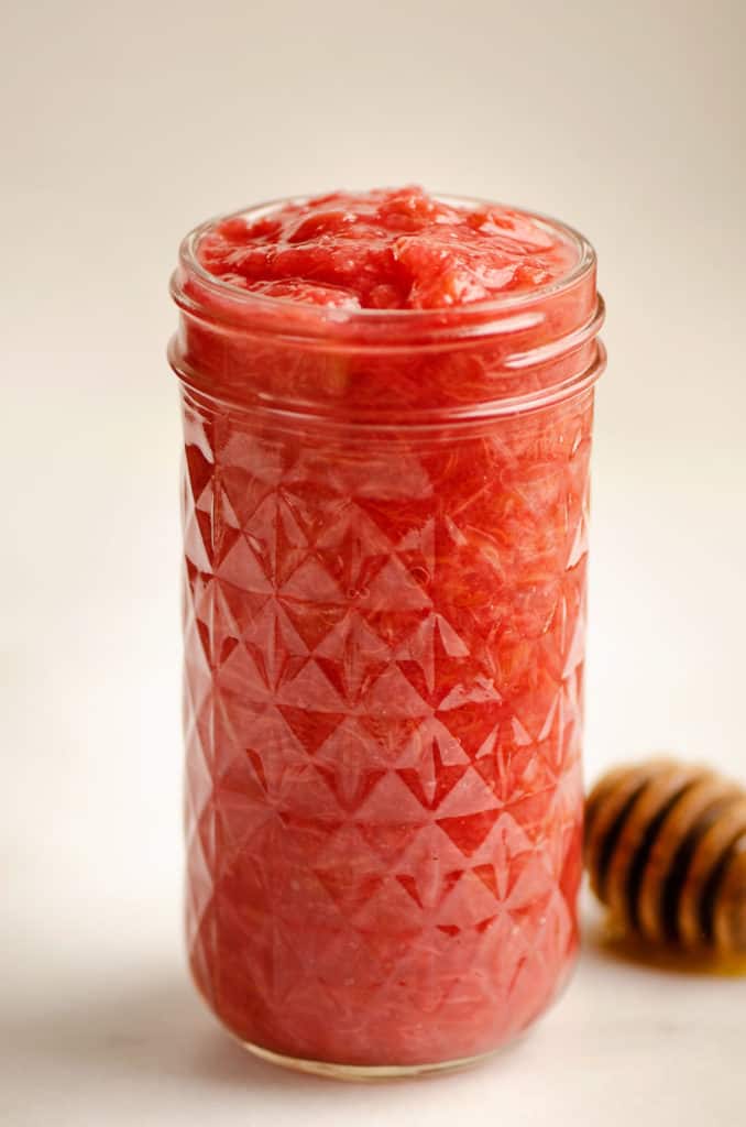 rhubarb sauce in glass jar with honey dipper