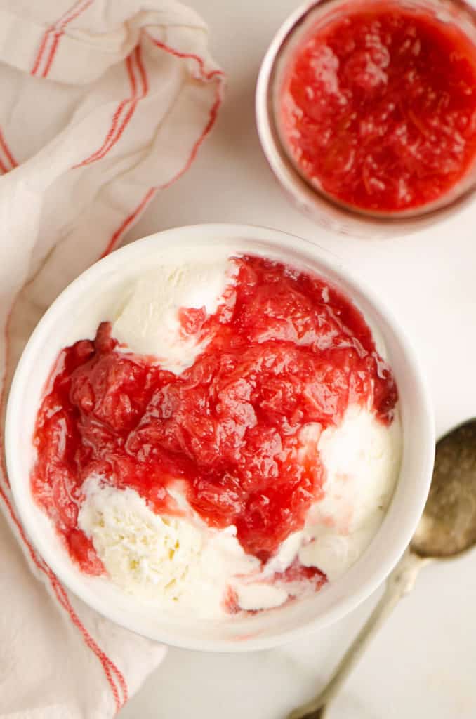 bowl of ice cream topped with rhubarb sauce on table