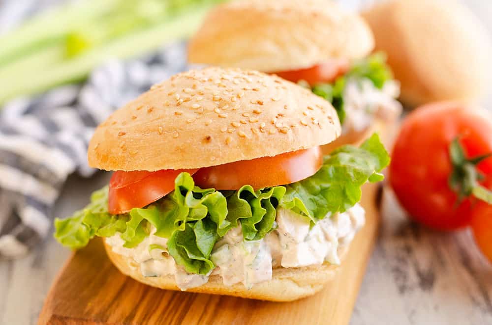 chicken salad sandwich on table with tomato and celery