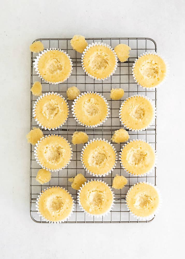 vanilla cupcakes wtih centers removed on cooling rack