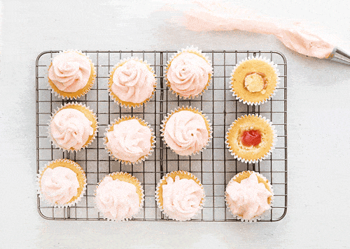 vanilla cupcakes topped with rhubarb jam and buttercream on cooling rack