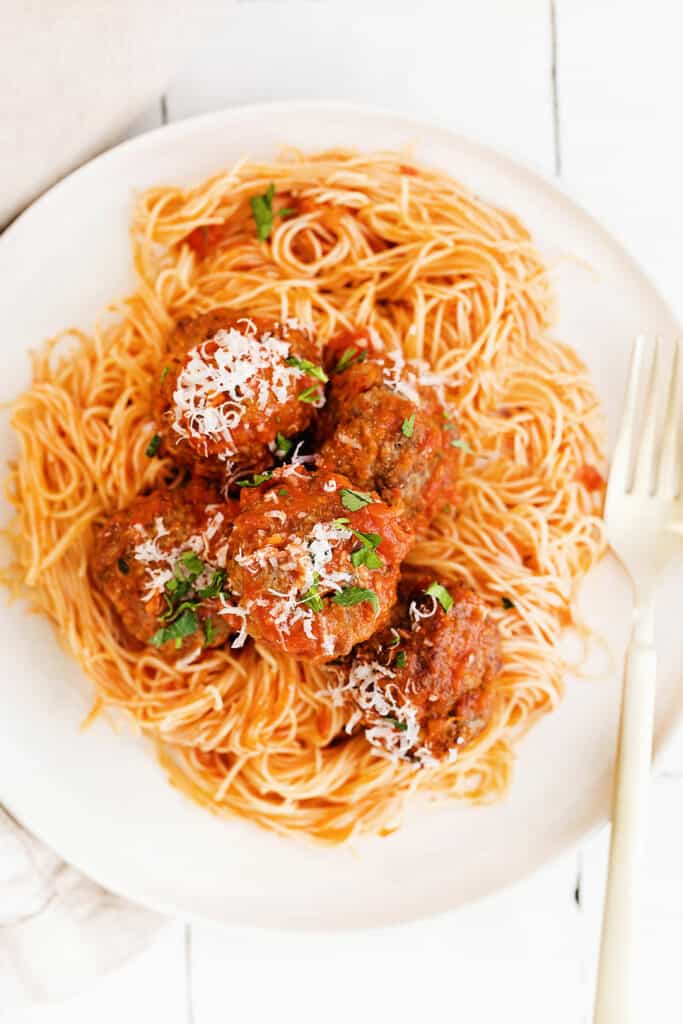 meatballs over pasta topped with grated parmesan cheese