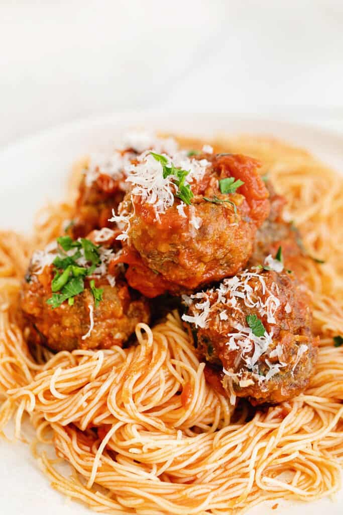 air fryer meatballs tossed in marinara over pasta and topped with parmesan and parsley