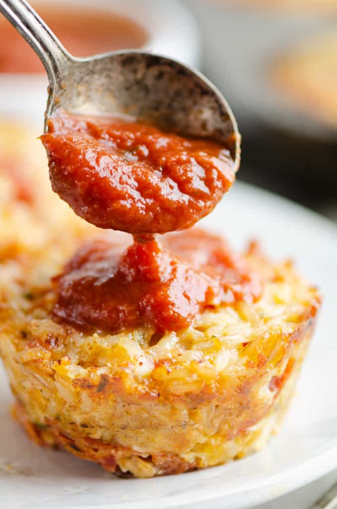 cheesy pizza rice muffin topped with spoonful of pizza sauce