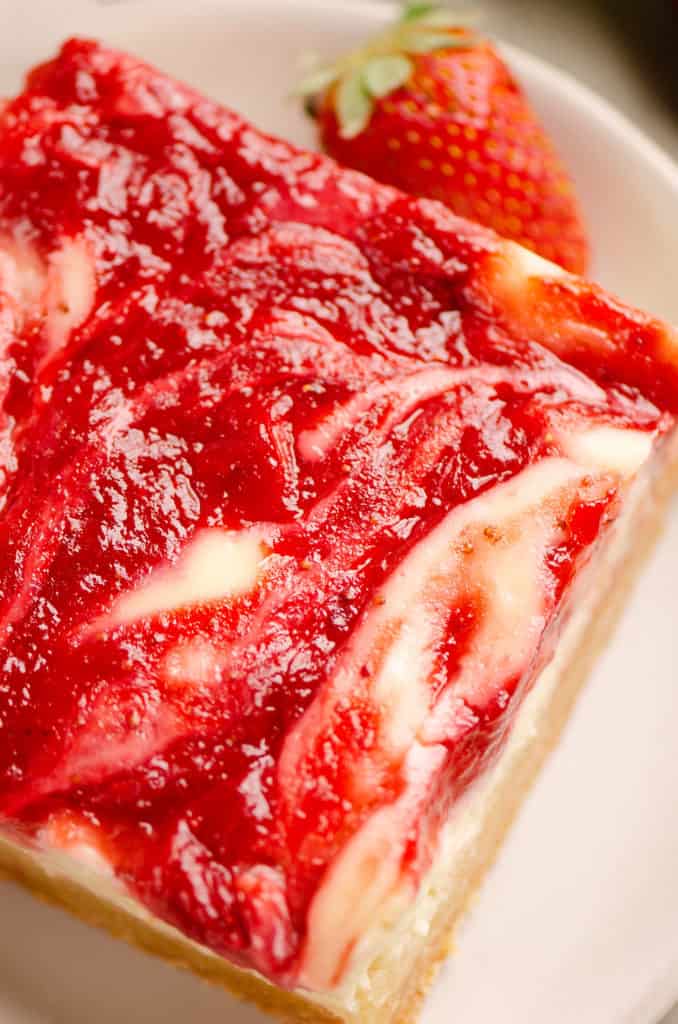 strawberry rhubarb cheesecake bar with swirl on plate with strawberry