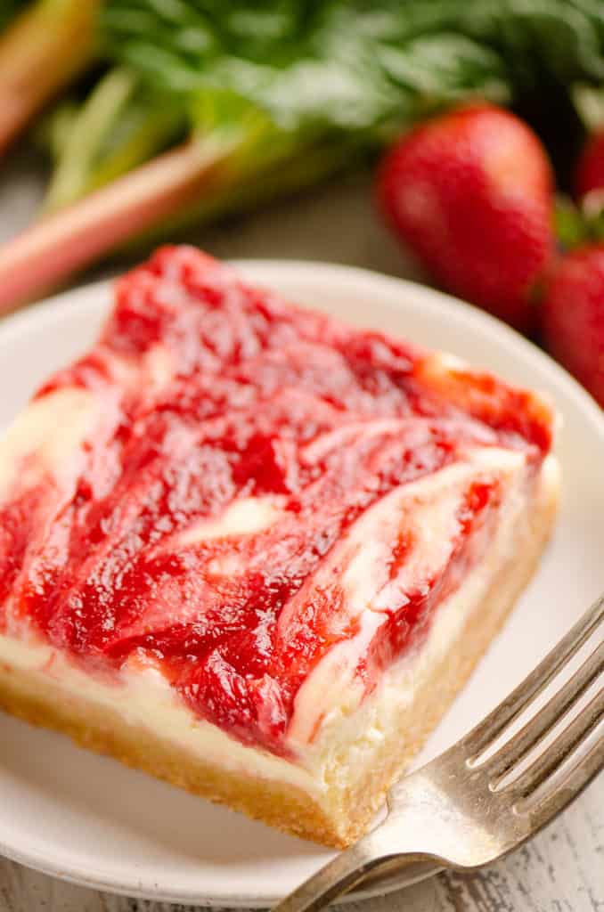 strawberry rhubarb cheesecake bar on white plate with fork