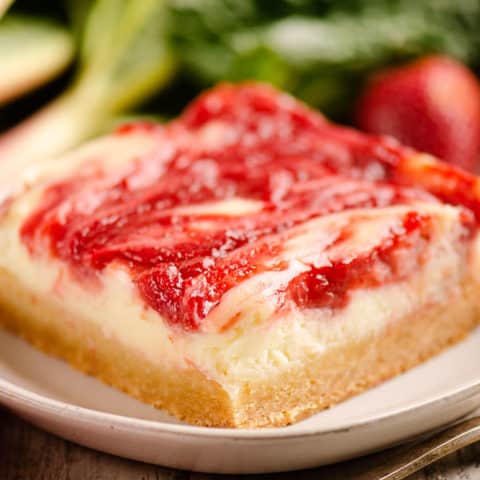 strawberry rhubarb cheesecake bar with sugar cookie crust on plate