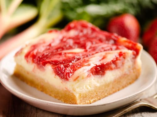 strawberry rhubarb cheesecake bar with sugar cookie crust on plate