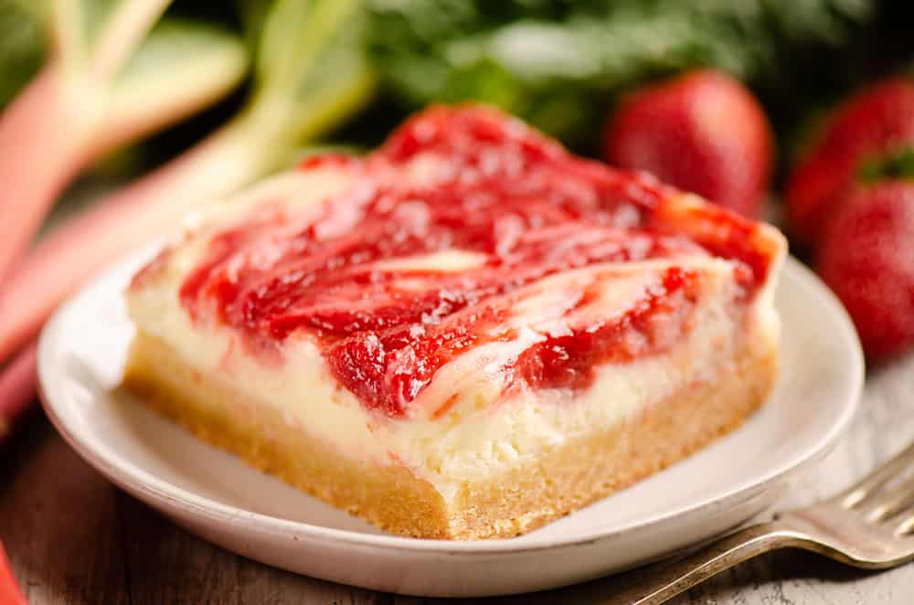 strawberry rhubarb cheesecake bar with sugar cookie crust on plate