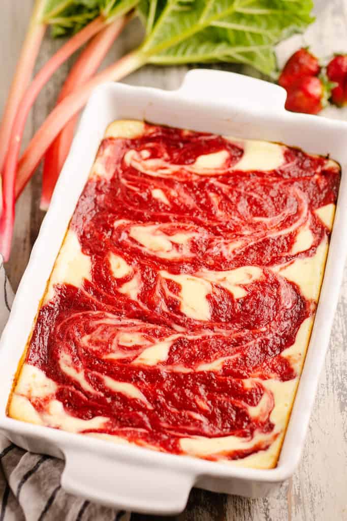 cheesecake bars in 9x13 pan with strawberries and rhubarb