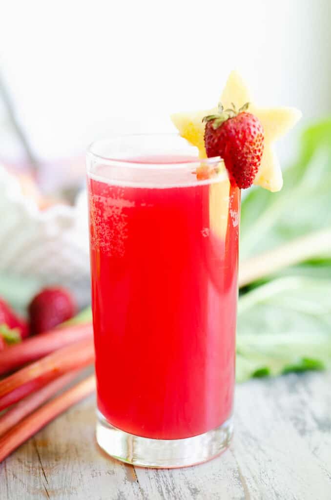 strawberry rhubarb punch in glass topped with pineapple and strawberry