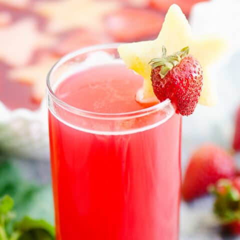 strawberry rhubarb punch in glass on table with strawberries