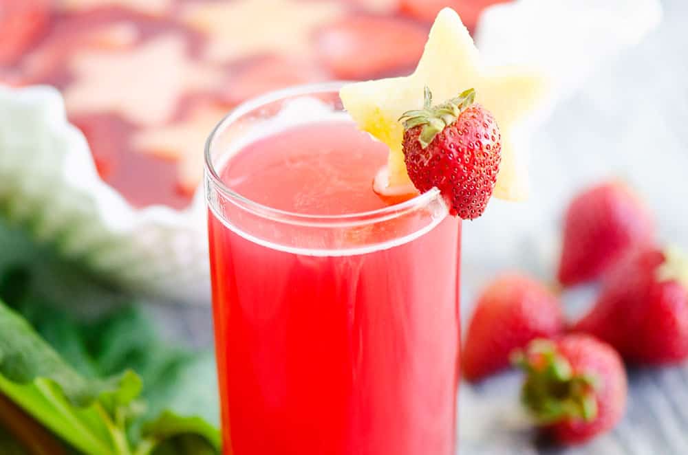 strawberry rhubarb punch in glass on table with strawberries