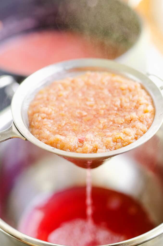 cooked rhubarb strained through metal mesh strainer