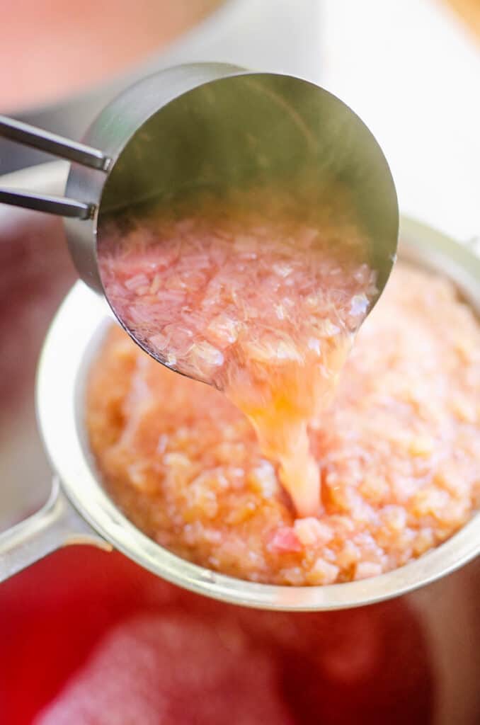 cooked rhubarb scooped in mesh strainer