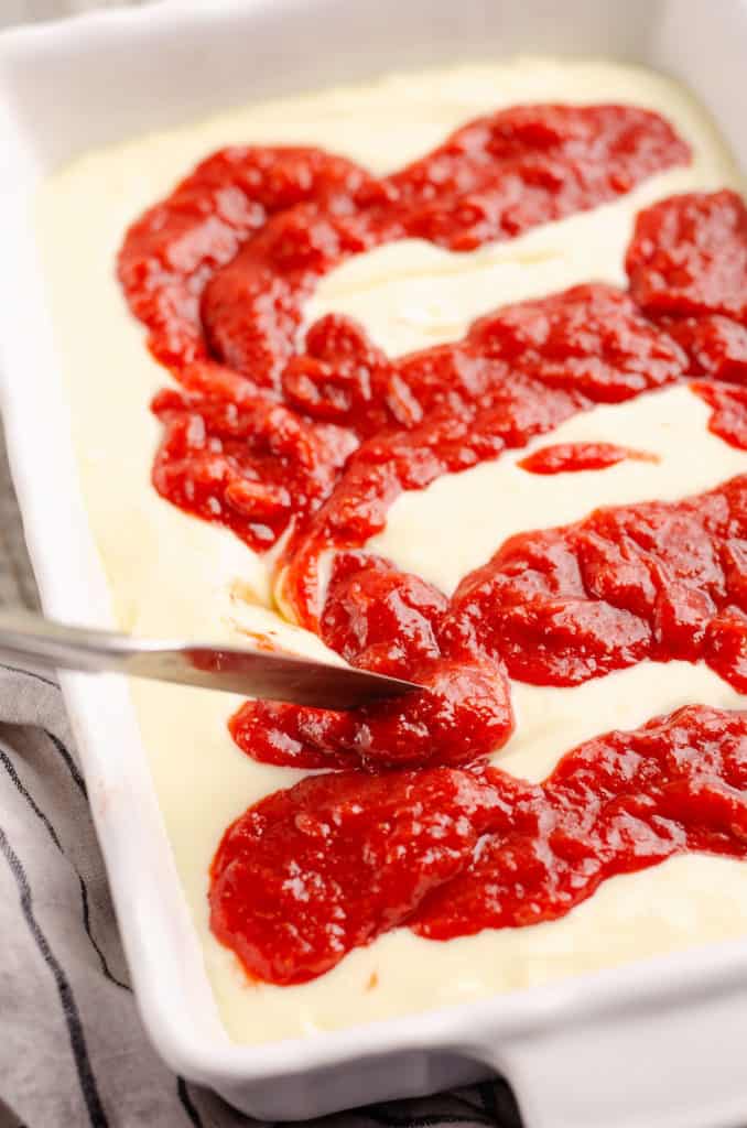 butter knife cut through cheesecake and strawberry rhubarb sauce