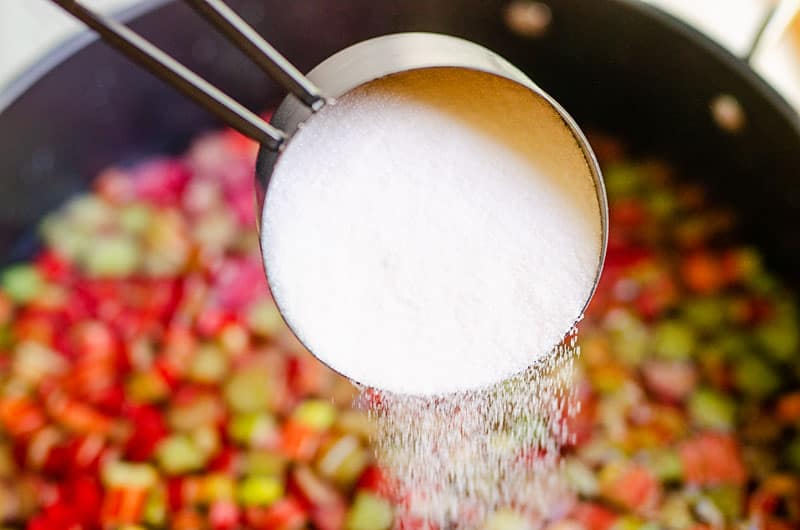 granulated sugar poured into pot with rhubarb and water