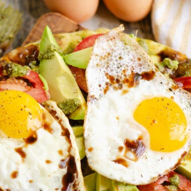 breakfast caprese flatbread topped with balsamic glaze on table with eggs