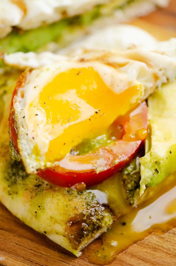 runny egg over tomato and avocado flatbread