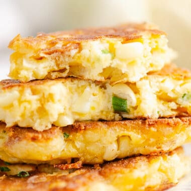 Corn fritter broken in half on stack of fritters