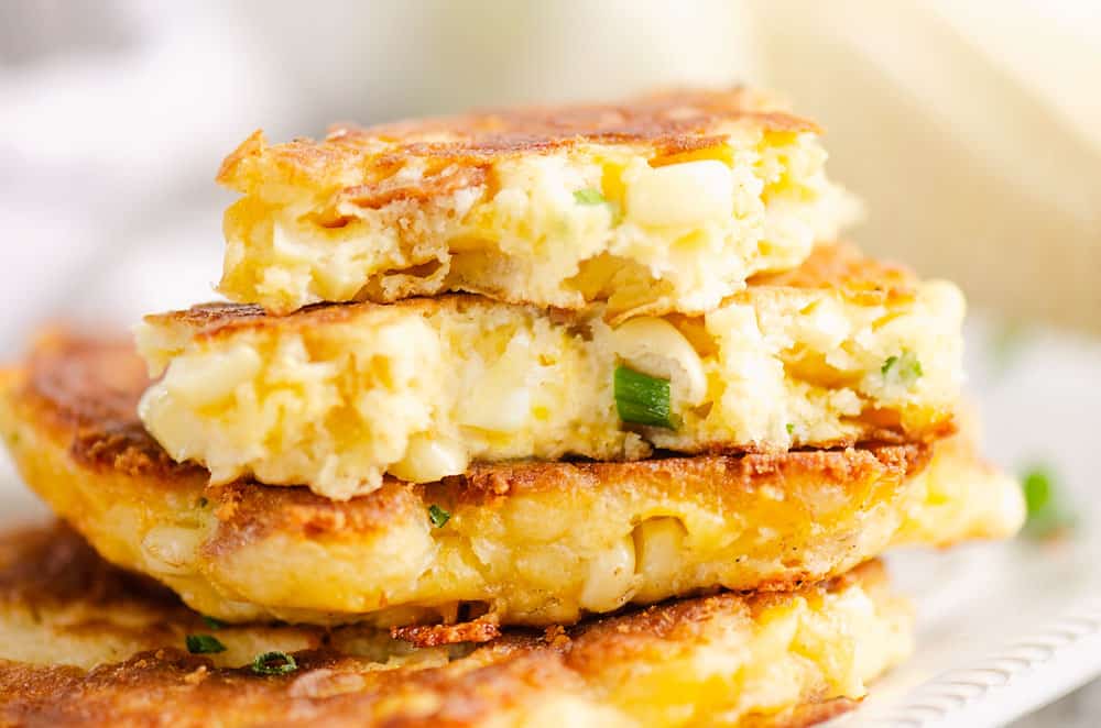 Corn fritter broken in half on stack of fritters