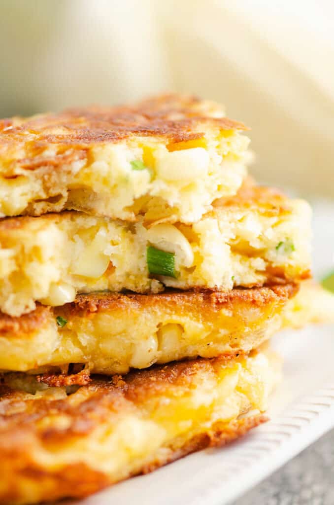 stack of corn fritters on plate with one broken in half