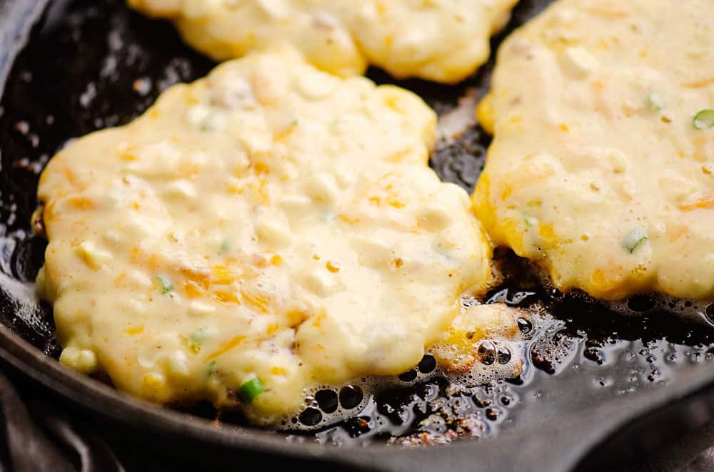 corn fritter sizzling in cast iron skillet