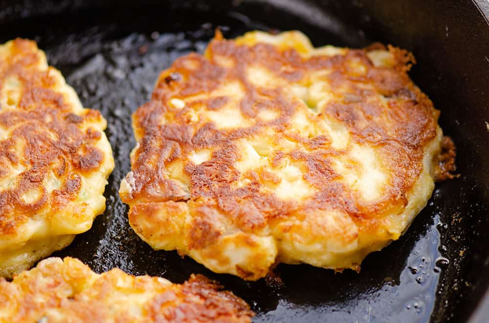 sweet corn fritter cooking in cast iron skillet