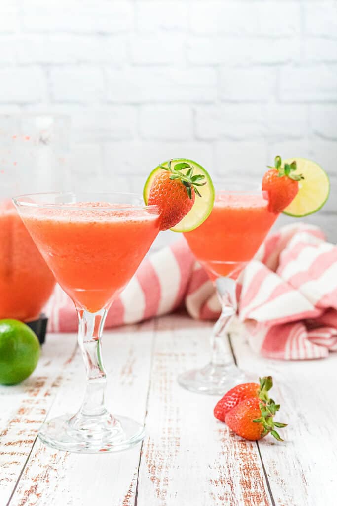 frozen daiquiris on table with limes and fresh strawberries