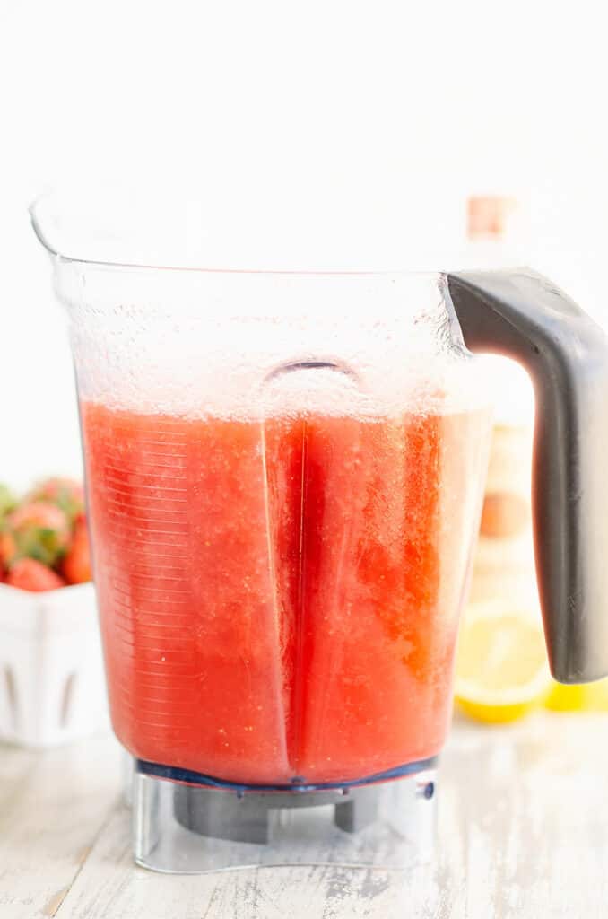 blender filled with frozen blended lemonade concentrate and strawberries