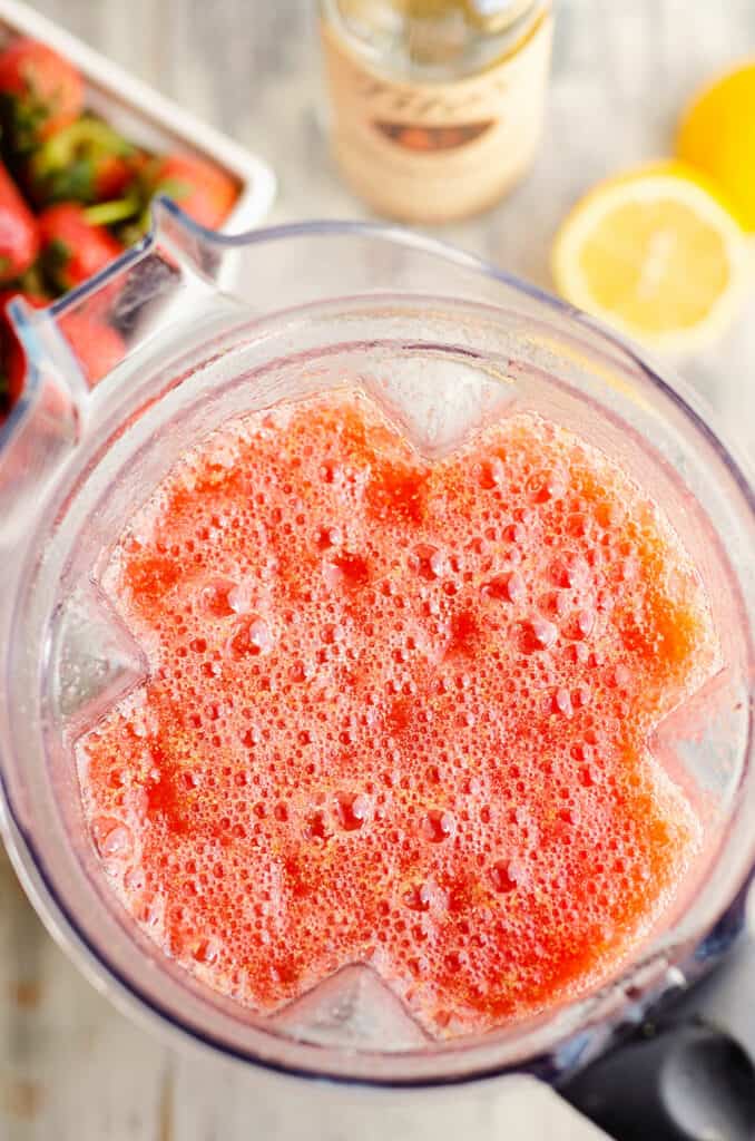 blender filled with blended lemonade concentrate and strawberries slush