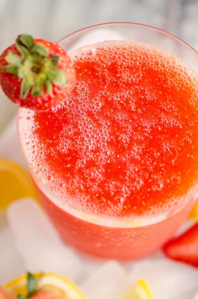 glass of frozen strawberry vodka lemonade slush topped with strawberry