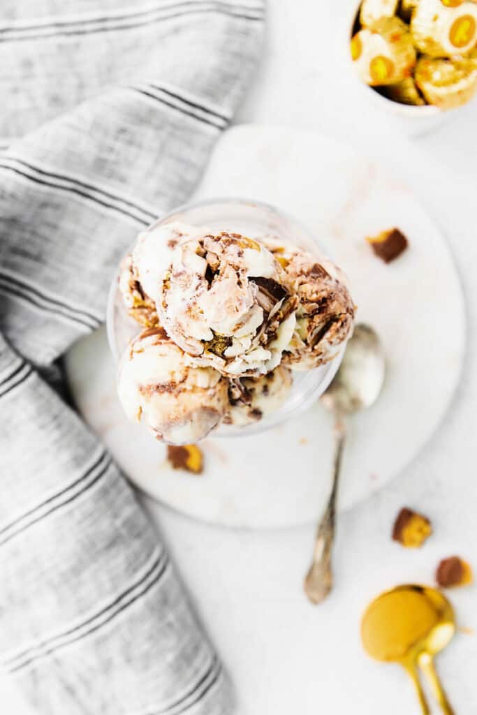 bowl of peanut butter cup ice cream on table with spoon and plate