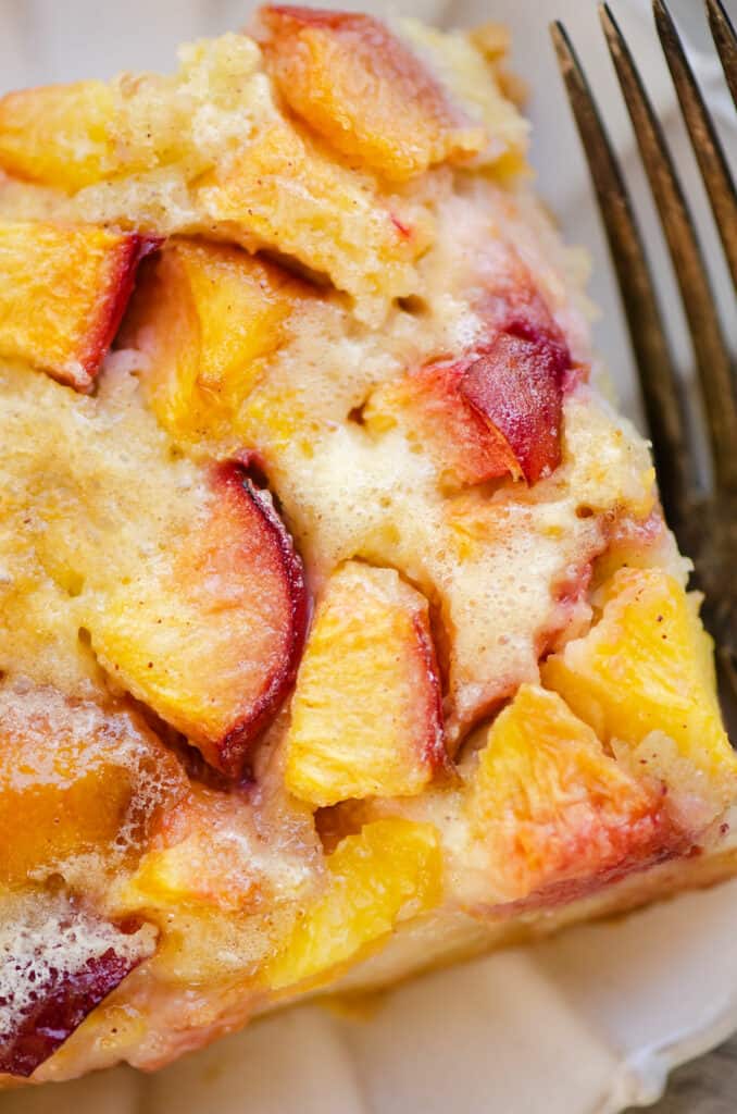 piece of peach custard dessert on plate with fork