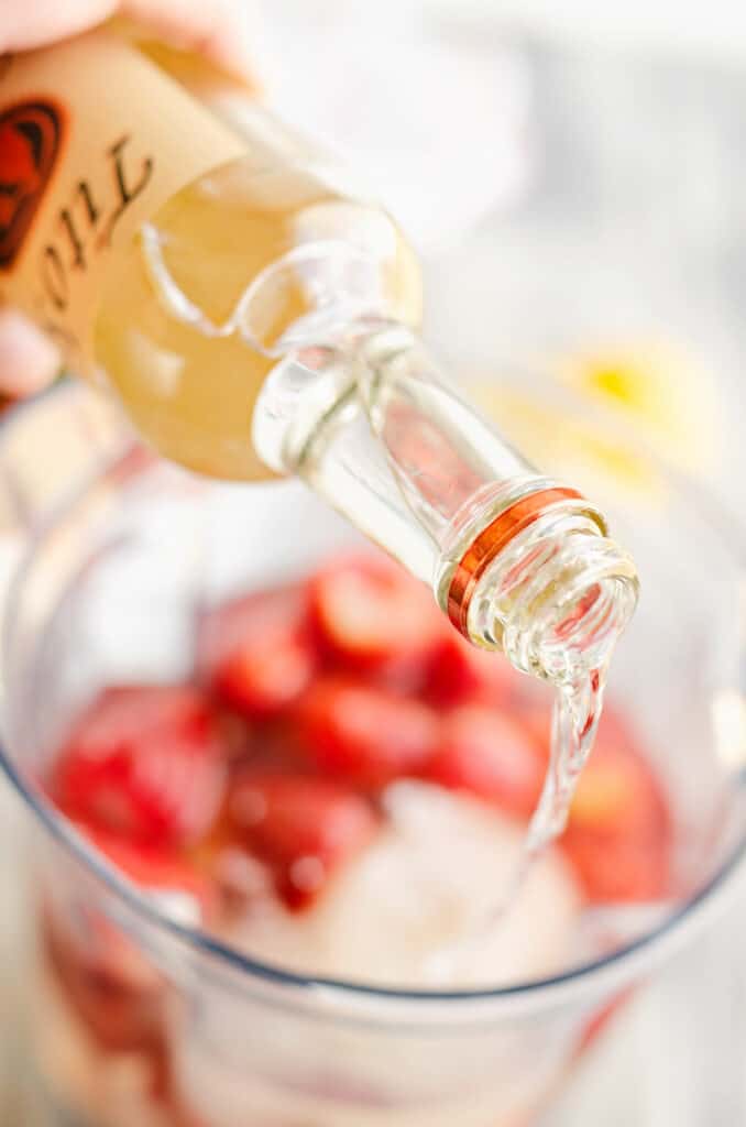 titos vodka poured into blender with strawberries