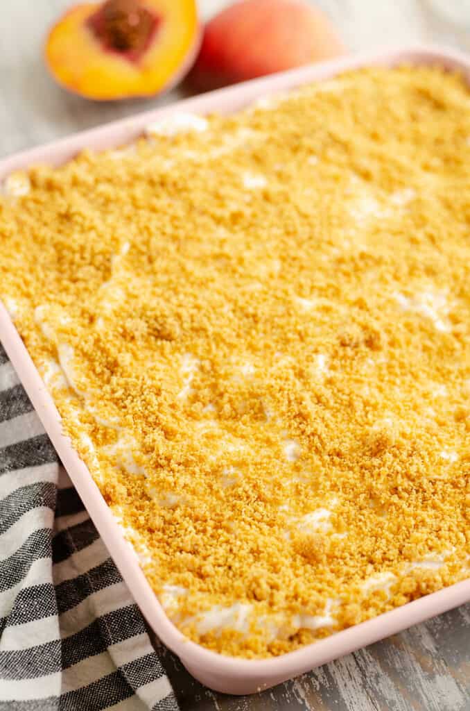 peaches and cream dessert topped with graham cracker crumbs