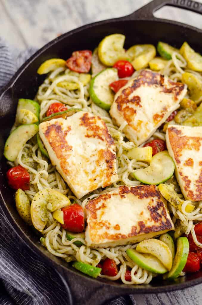 grilled halloumi cheese and pesto vegetable pasta in cast iron pan