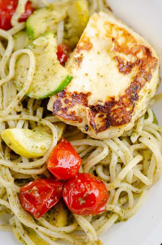 grilled halloumi cheese, vegetables and pesto spaghetti in bowl