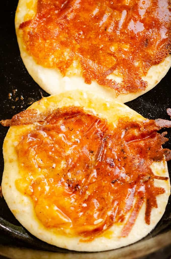 tortillas in cast iron pan topped with crispy cheese