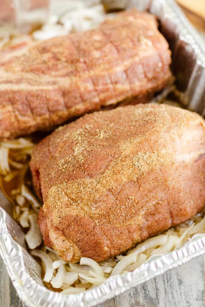 seasoned pork roast in pan with onions and broth