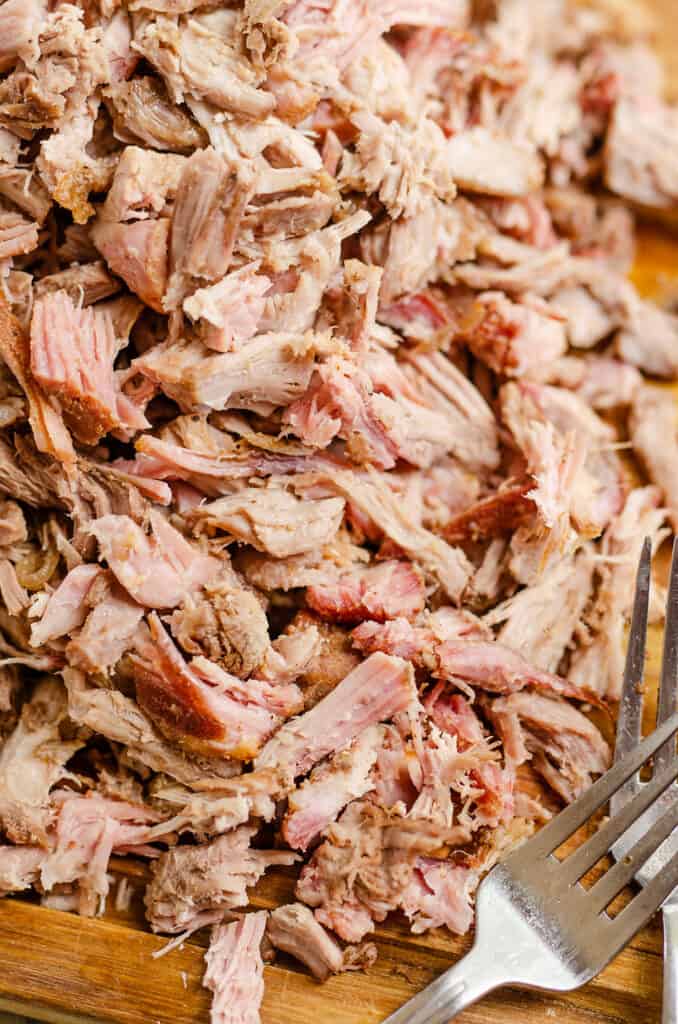 pork carnitas shredded with forks on cutting board