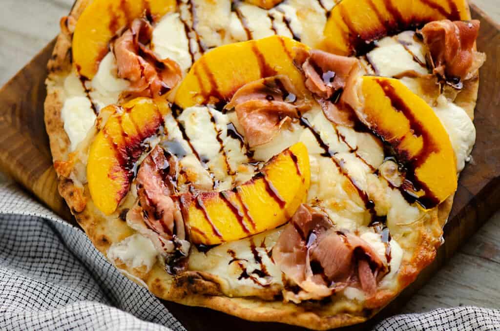 Naan Peach Pizza on cutting board drizzled with balsamic glaze